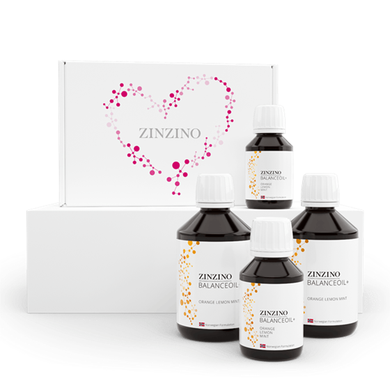 Cuatro botellas de Zinzino BalanceOil delante de una caja blanca con un corazón de puntos rosas y el logotipo de Zinzino sobre fondo blanco.